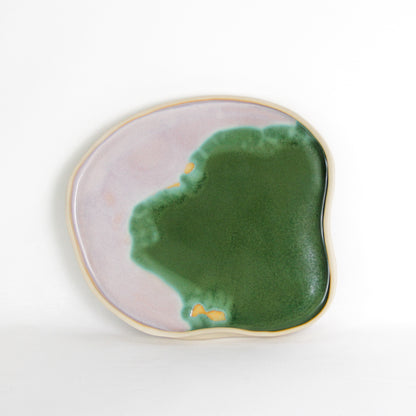 Image d'un plateau vert et rose en céramique artisanale. Sa forme est aléatoire et organique. Il mesure environ 27 cm de diamètre.