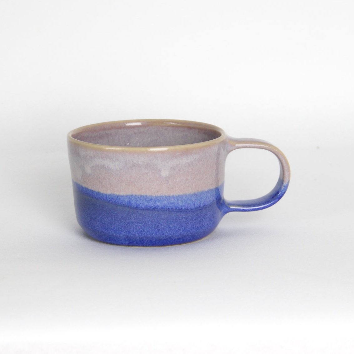 Image d'une tasse en grès bicolore. La tasse à café en céramique est rose et bleue et a une anse