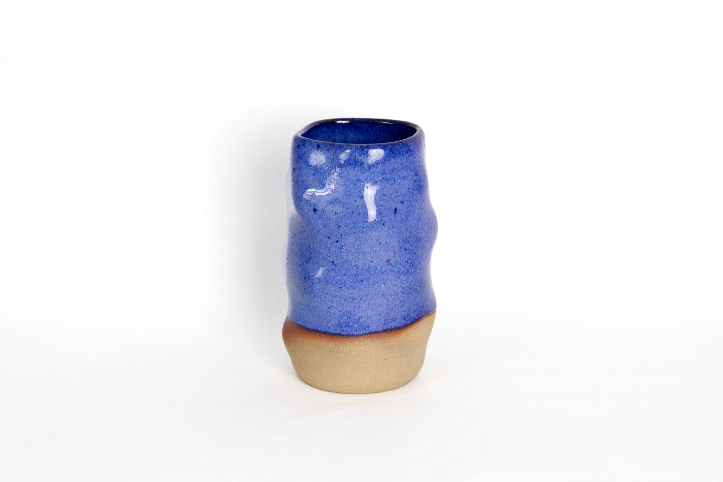 Image d'un vase en céramique bleu. Il est bi-matière car il est émaillé que sur la partie supérieure, on voit la terre sur le bas du vase. La vase est en grès artisanal