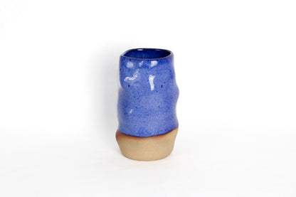 Image d'un vase en céramique bleu. Il est bi-matière car il est émaillé que sur la partie supérieure, on voit la terre sur le bas du vase. La vase est en grès artisanal