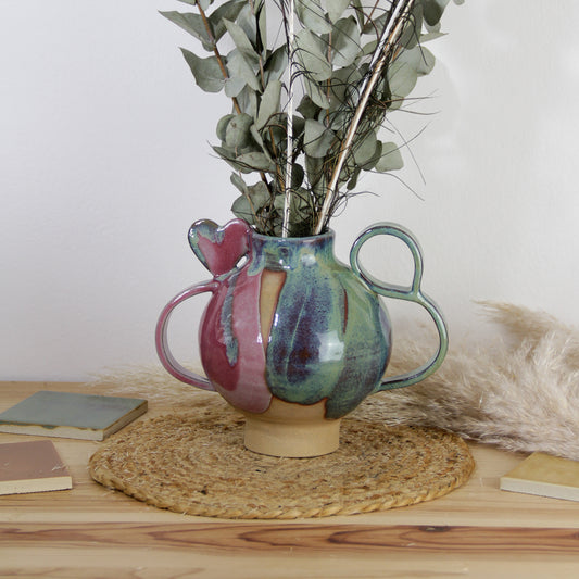 Image d'un vase rond avec des anses travaillé et un coeur. Le vase en céramique est bicolore et modelé à la main