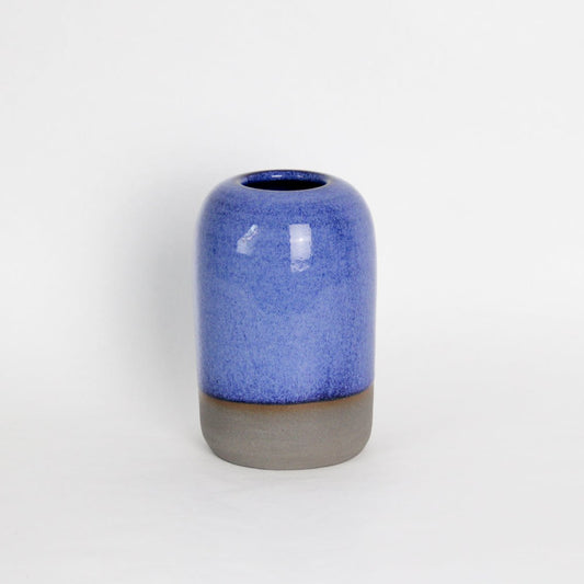 Image d'un soliflore en grès foncé. La pièce en céramique est de couleur bleue. C'est un objet déco ou un vase de table.